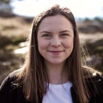 Blid kvinne med brunt langt hår. Foto. 