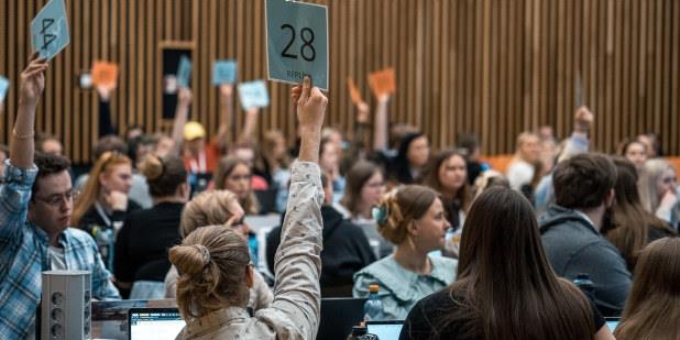 Studenter voterer med blå og oransje skilt. Foto. 